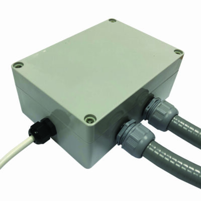 Plastic rectangular electrical junction box sits with three cables attached through threaded cable glands, two gray flexible conduits and a white cable extending from sides, photographed on a white background.