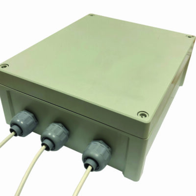 A rectangular beige outdoor electrical junction box sits angled on a white background, three grey cable glands secure white cables into its front face, screw-fastened lid with rounded corners.